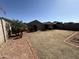 Large backyard features a mix of gravel, brick, and dormant grass, plus perimeter vegetation at 10247 W Hilton Ave, Tolleson, AZ 85353