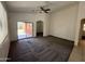 Bright living room with carpet flooring, ceiling fan, and sliding glass door leading to the patio at 10247 W Hilton Ave, Tolleson, AZ 85353