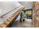 A modern staircase with wood steps, a glass railing, and an open design with a stone accent wall at 10283 E Running Deer Trl, Scottsdale, AZ 85262