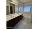 Bathroom featuring double sinks, tile flooring, a tub, and natural light from the window at 12571 W Clarendon Ave, Avondale, AZ 85392