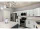 Well-equipped kitchen showcasing white cabinetry, stainless steel appliances, and an island with a waterfall countertop at 12571 W Clarendon Ave, Avondale, AZ 85392