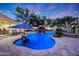 Resort-style pool featuring a tranquil waterfall, lush landscaping, and ambient lighting for evening enjoyment at 1423 E Beverly Ln, Phoenix, AZ 85022