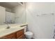 Bright bathroom featuring a wood vanity, sink, large mirror, toilet, and shower with curtain at 16112 W Buchanan St, Goodyear, AZ 85338