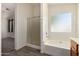 Bright bathroom featuring a bathtub with shower and glass doors and view to bedroom at 16112 W Buchanan St, Goodyear, AZ 85338