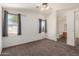 This main bedroom offers a neutral carpet, ceiling fan, and view to the ensuite bathroom at 16112 W Buchanan St, Goodyear, AZ 85338