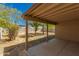 This covered patio overlooks the backyard with a dirt landscape, block fence, and trees at 16112 W Buchanan St, Goodyear, AZ 85338
