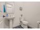 Clean half bathroom featuring a pedestal sink, modern toilet, and stylish black tile floors at 17396 W Crawfordsville Dr, Surprise, AZ 85388