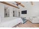 Bedroom with wood beams, door to bathroom, and large television on the wall at 17396 W Crawfordsville Dr, Surprise, AZ 85388