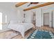 Bedroom with wood beams, wood floor, and doorway to the ensuite bathroom at 17396 W Crawfordsville Dr, Surprise, AZ 85388