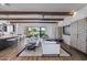 Open-concept living space with hardwood floors, wood beams, white sofas, and backyard view at 17396 W Crawfordsville Dr, Surprise, AZ 85388