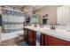 Bathroom with double vanity sinks, a framed mirror, and a bathtub with a shower at 17517 W Dahlia Dr, Surprise, AZ 85388