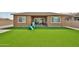 Expansive artificial grass backyard with covered patio and block wall, ideal for Gathering enjoyment at 23871 N 167Th Ln, Surprise, AZ 85387