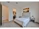 Neutral bedroom boasts carpet flooring, a large window, a cozy bed with side tables, and an adjoining laundry closet at 23871 N 167Th Ln, Surprise, AZ 85387