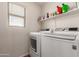 Efficient laundry room featuring modern washer and dryer with shelving for storage at 3272 E Tyson St, Gilbert, AZ 85295