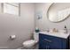 Stylish powder room with blue vanity, gold fixtures, and a contemporary round mirror at 3272 E Tyson St, Gilbert, AZ 85295