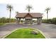 Stone gate house entrance with desert landscaping on a circular median, palm trees, and paved streets at 3306 E Jaeger Cir, Mesa, AZ 85213