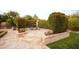 A stone patio with a table and chairs surrounded by lush greenery and garden features at 3306 E Jaeger Cir, Mesa, AZ 85213