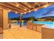 The backyard offers a stainless steel outdoor kitchen, covered patio, and a well-lit pool and spa area at 4876 N 207Th Ln, Buckeye, AZ 85396