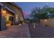 This backyard features hardscaping, landscaping, lighting, a wrought iron fence, and an exterior view of the home at 4876 N 207Th Ln, Buckeye, AZ 85396