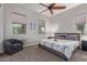 Bedroom with large windows, a gray accent chair, and a ceiling fan at 4876 N 207Th Ln, Buckeye, AZ 85396