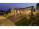 Well-maintained home at dusk features a manicured lawn, desert landscaping, and a brick-paved driveway at 4876 N 207Th Ln, Buckeye, AZ 85396