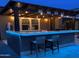 Outdoor kitchen with a pergola and bar illuminated with lights and seating at 4876 N 207Th Ln, Buckeye, AZ 85396