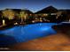 Inviting backyard pool glows at twilight, surrounded by lush desert landscaping and accent lighting at 4876 N 207Th Ln, Buckeye, AZ 85396