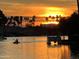 Scenic waterfront view with palm trees silhouetted by a vibrant sunset with a kayaker enjoying the waterway at 518 S Bay Shore Blvd, Gilbert, AZ 85233