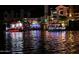 Houses decked with holiday lights reflected in the water with a festive boat parade at night at 518 S Bay Shore Blvd, Gilbert, AZ 85233