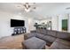 Open concept living room features a large sectional couch, ceiling fan, and tile flooring throughout at 697 E Ruby Dr, Casa Grande, AZ 85122