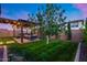 Beautiful backyard featuring green grass, brick patio, pergola, and lush landscaping at 6983 W Andrea Dr, Peoria, AZ 85383