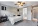 Neutral bedroom with a ceiling fan, carpet, a view to the bathroom, and two dark colored nightstands at 6983 W Andrea Dr, Peoria, AZ 85383