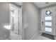 Bright hallway featuring tiled floors, a bathroom entrance, and front door with glass inserts at 6983 W Andrea Dr, Peoria, AZ 85383