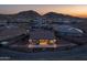 Aerial view of the back of a home with patio and desert views at dusk at 7659 S 164Th Ln, Goodyear, AZ 85338