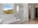 Bright bathroom featuring a soaking tub, glass shower, and natural light through the window at 7659 S 164Th Ln, Goodyear, AZ 85338