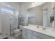 Bright bathroom featuring glass enclosed shower, white vanity and toilet with shelving unit at 7659 S 164Th Ln, Goodyear, AZ 85338
