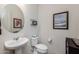 Well-lit powder room featuring pedestal sink and round mirror and tasteful wall art at 7659 S 164Th Ln, Goodyear, AZ 85338