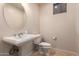 Neutral-toned powder room featuring pedestal sink, round mirror, elongated toilet and tiled floors at 8149 N 13Th Pl, Phoenix, AZ 85020