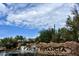 Landscaped community entrance with stone signage, waterfall, and lush desert vegetation under a partly cloudy blue sky at 12062 W Duane Ln, Peoria, AZ 85383