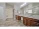 Bathroom featuring a large mirror, wood cabinets, and a neutral tile floor at 43324 W Desert Fairways Dr, Maricopa, AZ 85138