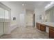 Bright bathroom with a soaking tub, walk-in shower, dual vanity, and tile flooring at 43324 W Desert Fairways Dr, Maricopa, AZ 85138
