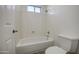 Well-lit bathtub and toilet in a bathroom with a window and showerhead at 43324 W Desert Fairways Dr, Maricopa, AZ 85138