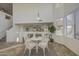 Bright dining area with tile floors and a table with white chairs situated under a modern light fixture at 43324 W Desert Fairways Dr, Maricopa, AZ 85138