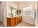 Bright bathroom featuring a spacious vanity with wood cabinets and a unique glass block window for natural light at 10903 E Ocaso Ave, Mesa, AZ 85212