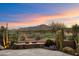 Backyard with stone firepit and views of the golf course at sunset at 11240 E Apache Vistas Dr, Scottsdale, AZ 85262