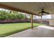 Covered patio looks out to large backyard, and mature trees with a wood retaining wall at 11243 E Jenan Dr, Scottsdale, AZ 85259