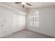 Bedroom features neutral carpet, ceiling fan, shuttered arched window and closet at 11243 E Jenan Dr, Scottsdale, AZ 85259