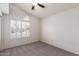 Bright bedroom features neutral carpet, modern fan and lovely shuttered arched window at 11243 E Jenan Dr, Scottsdale, AZ 85259
