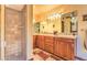 Well-lit bathroom showcasing double vanity, warm wood cabinets, and walk-in shower with tile surround at 12646 N 80Th Pl, Scottsdale, AZ 85260