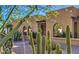 Tan stucco home featuring desert landscaping with cacti and trees, arched windows, and stone pathway at 12646 N 80Th Pl, Scottsdale, AZ 85260